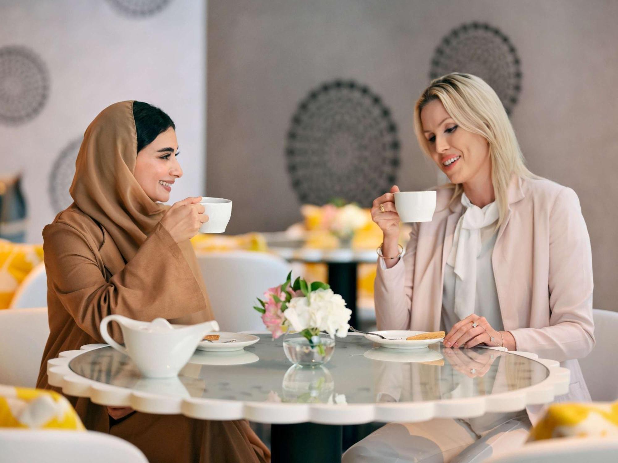 Moevenpick Hotel & Apartments Ghala Маскат Экстерьер фото Two women drinking coffee